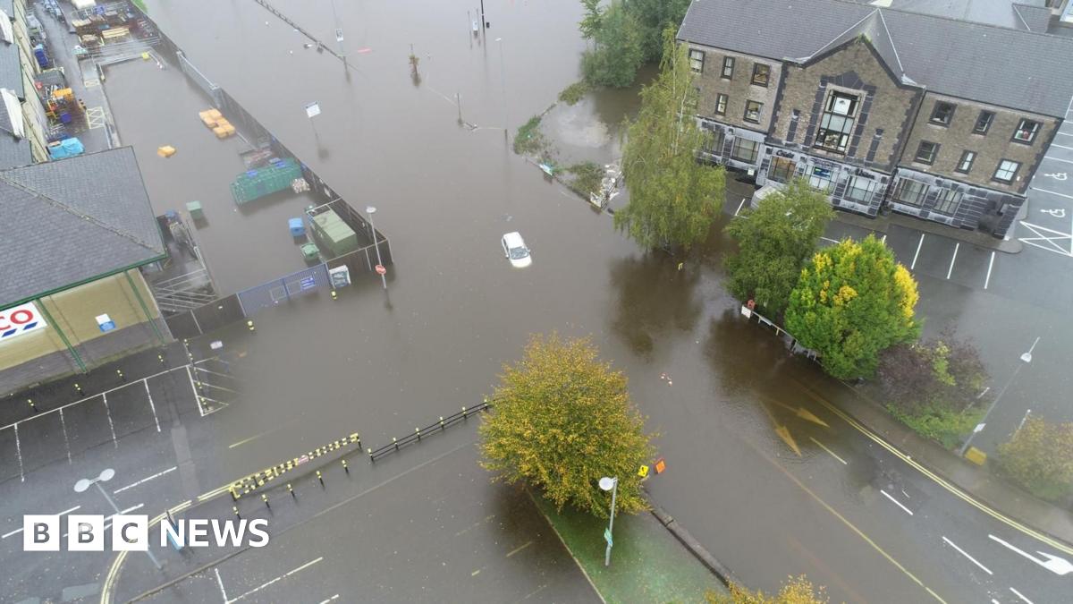 An aerial shot shows a car submerged in floodwater.