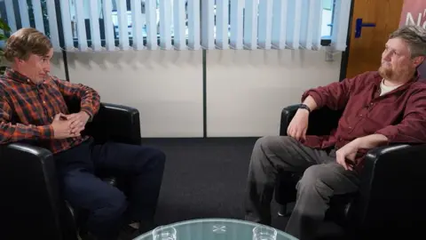 Alan Partridge sitting down opposite his old sidekick, Simon