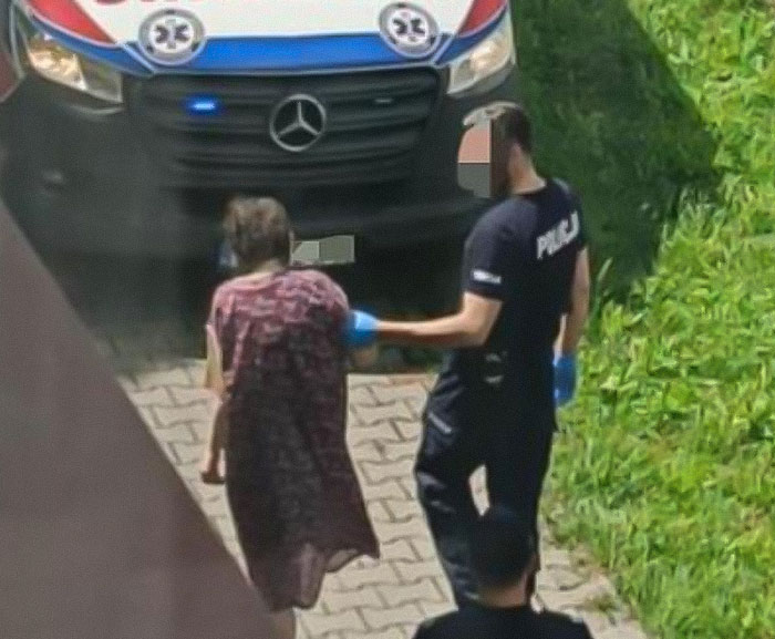 Police officer escorting a teen missing 27 years from parents’ house in a distressing condition near ambulance.