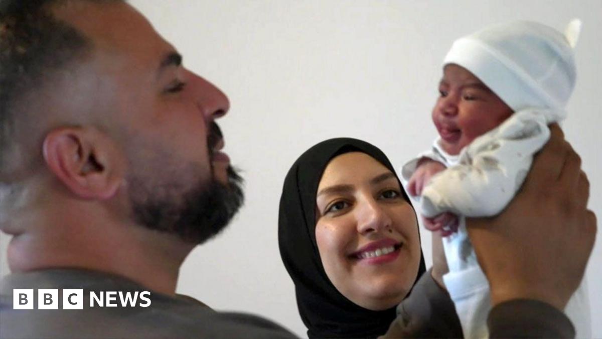 Ahmed with his wife, Nour and teenage daughter, Rahaf. They are all happy and focused on a sleeping newborn baby, being held by Ahmed and wrapped in a cream coloured blanket.