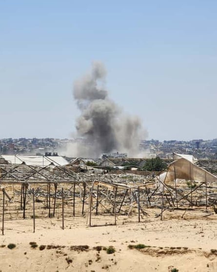 Smoke rises in the distance with the ruins of a camp in the foreground.