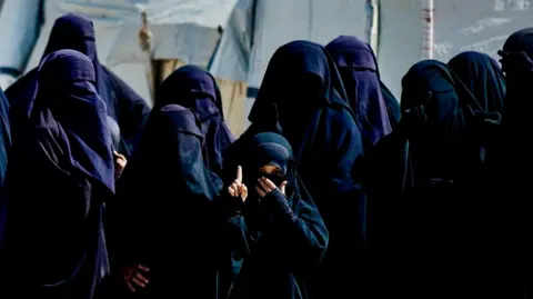 Goktay Koraltan/BBC Several veiled women and children, clad head to toe in black, at the camp. 