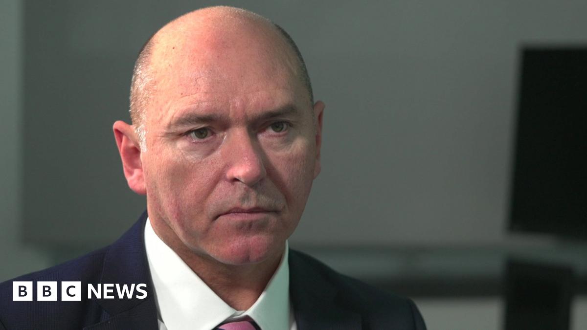 A photo of Karen Booth, smiling broadly with her head tilted. She has blonde hair with a sweeping fringe and the image is closely cropped showing her face and neck.