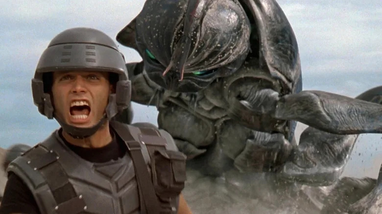 A giant bug sneaking up behind Johnny Rico in Starship Troopers