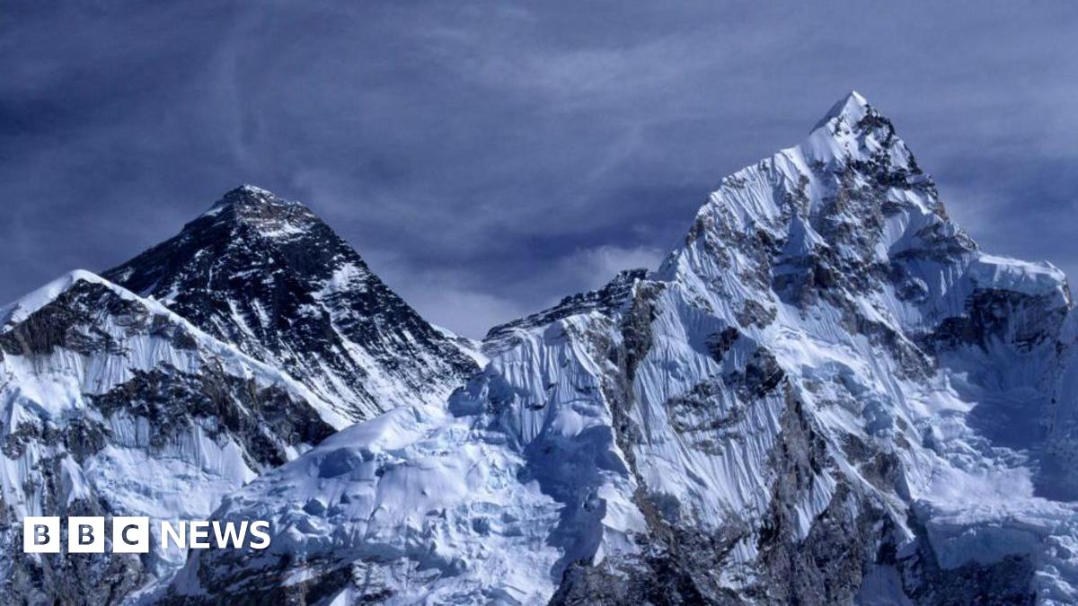 Mount Everest. Two mountain peaks covered in snow. The sky is dark blue and it looks stormy.