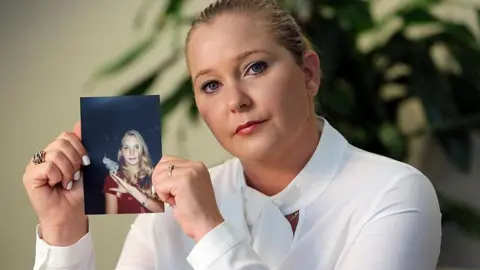 Getty Images Virginia Giuffre holding a picture of herself as a teenager