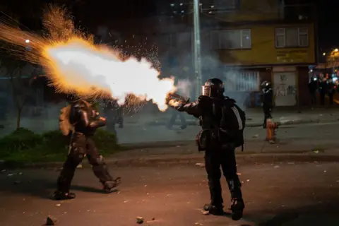 Getty Images A police officer seen firing tear gas into a crowd of protesters during anti government demonstrations in 2021