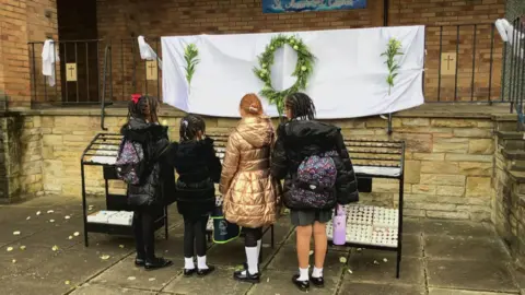 School children light candles outside St Anne's Catholic church