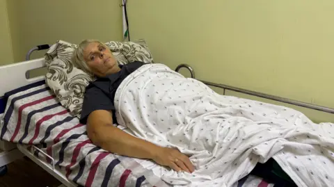 Iona Hampson/BBC Olha Zolotova lying injured in a hospital bed
