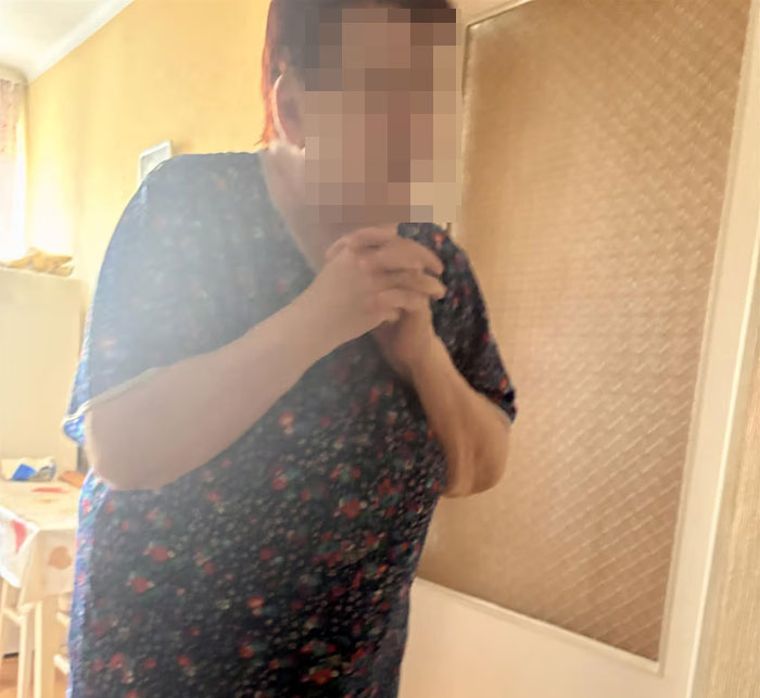 Woman in a cluttered, dimly lit room depicting teen missing 27 years discovered living in parents’ house condition.