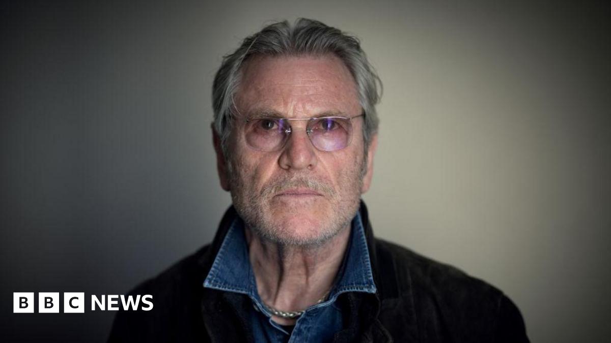 A photo of Tchéky Karyo, taken at La Baule film festival in July 2022 - he has grey hair, a beard and wears glasses and a denim shirt.