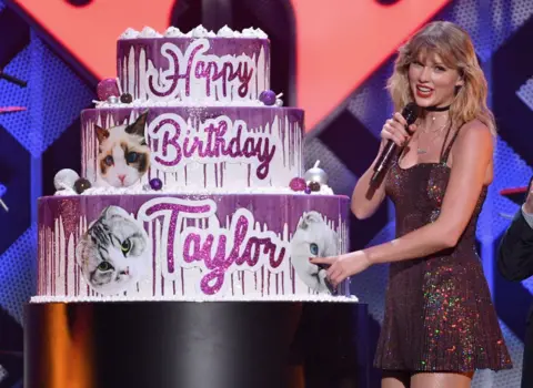 Getty Images Taylor Swift by a giant birthday cake on stage