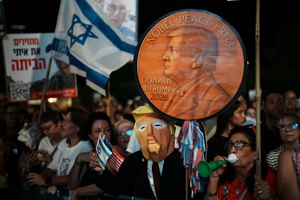 A man wearing a Donald Trump mask holds a sign backing the US president for the Nobel Peace Prize in Tel Aviv.
