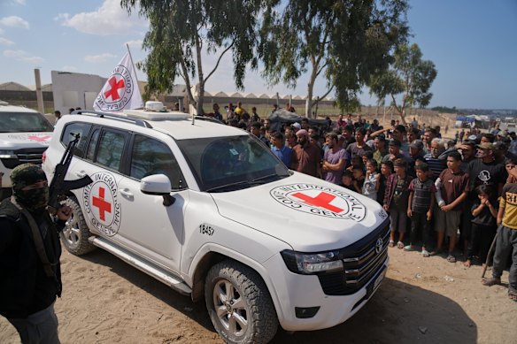 ICRC vehicles carrying released Israeli hostages make their way through groups of Palestinians and Hamas gunmen on their way to the Israeli border, in Khan Younis.