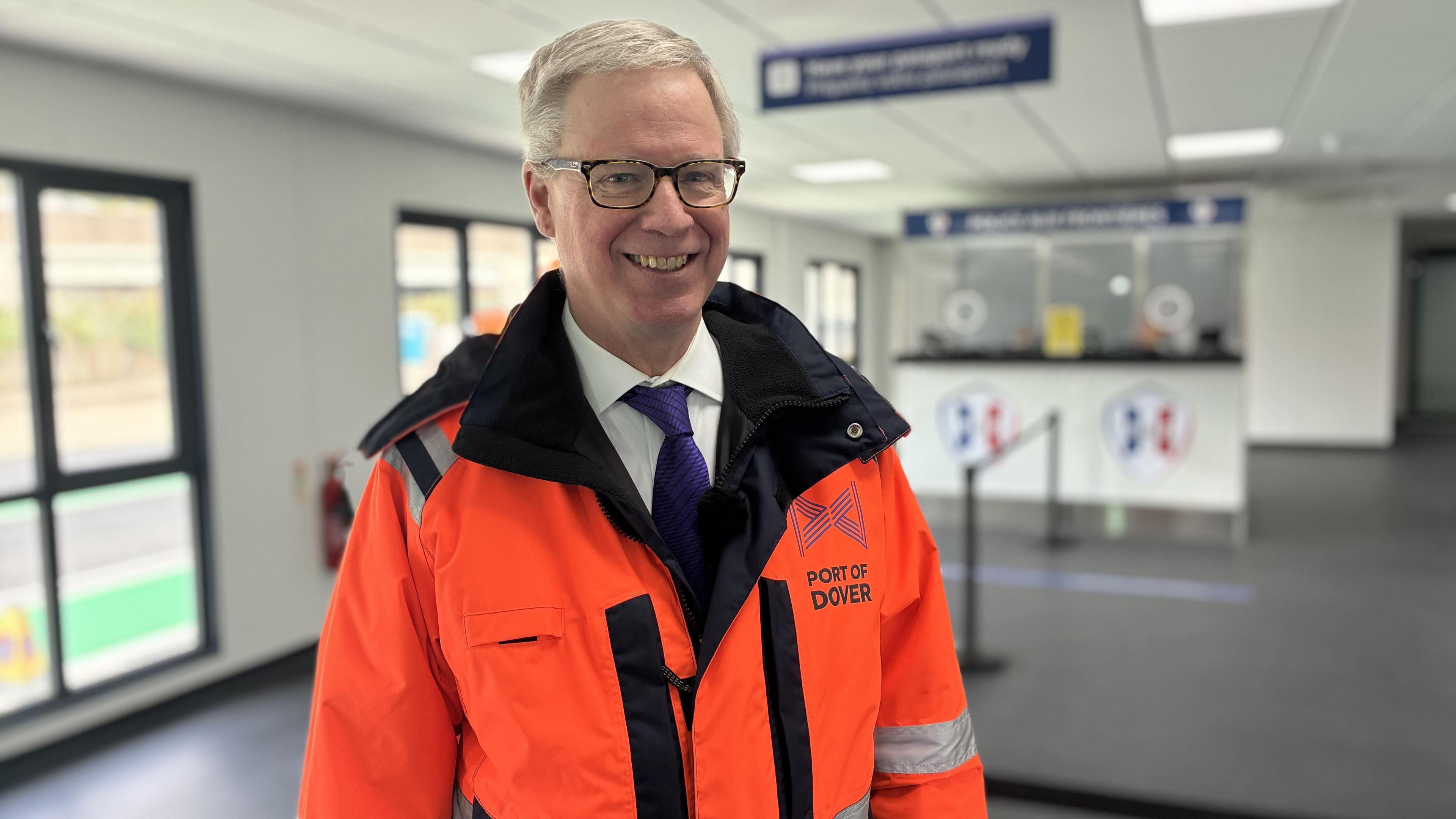 Doug Bannister CEO Port of Dover in hi vis jacket and tie smiling inside the new terminal area