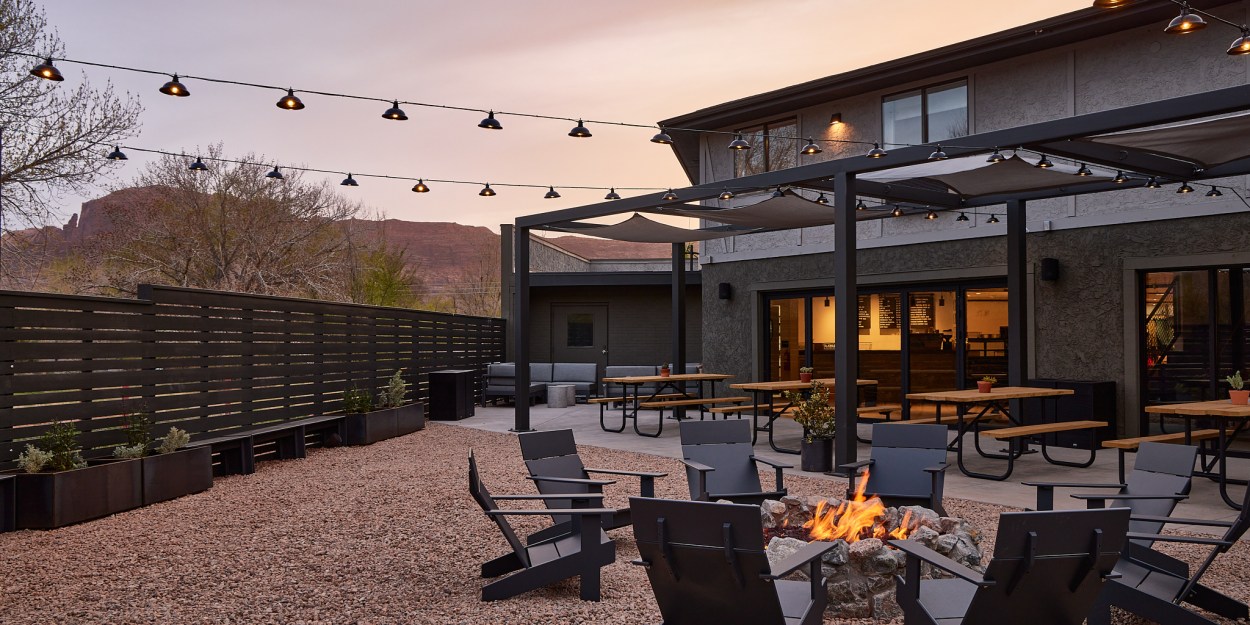 Chairs gathered around a firepit, with picnic tables and building in background