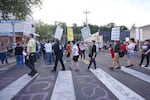 Protesters hold signs walking along the crosswalk that leads to the Immigration and Customs Enforcement facility in Portland, Ore., on Sept. 28, 2025.