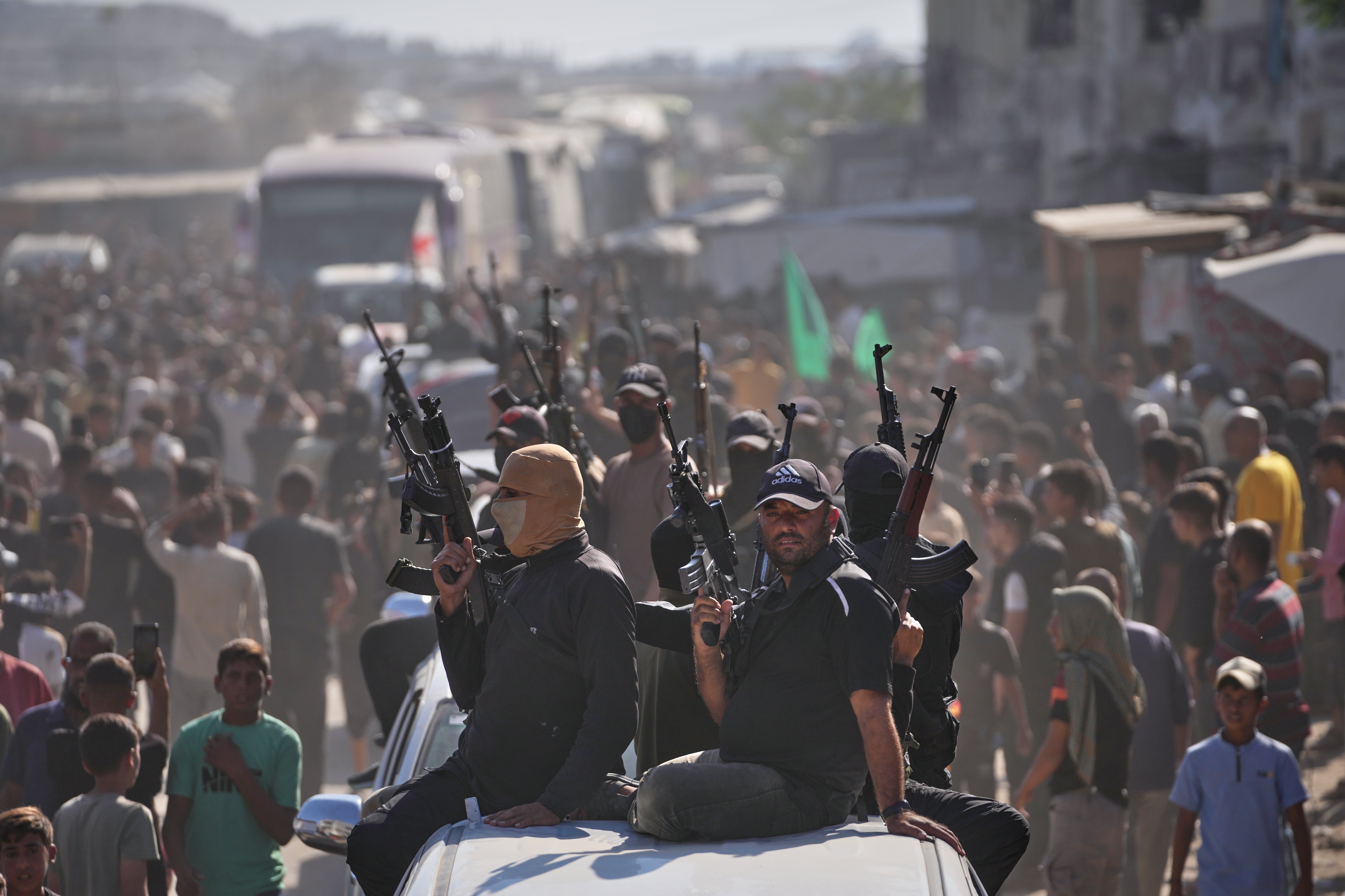 Hamas gunmen on pickup trucks escort buses carrying freed Palestinian prisoners as they are greeted following their release from Israeli jails under a cease-fire agreement between Hamas and Israel, in Khan Younis, southern Gaza Strip, Monday, Oct. 13, 2025. (AP Photo/Jehad Alshrafi)