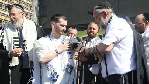 Former hostage Bar Kupershtein leads tefillin ceremony in Tel Aviv