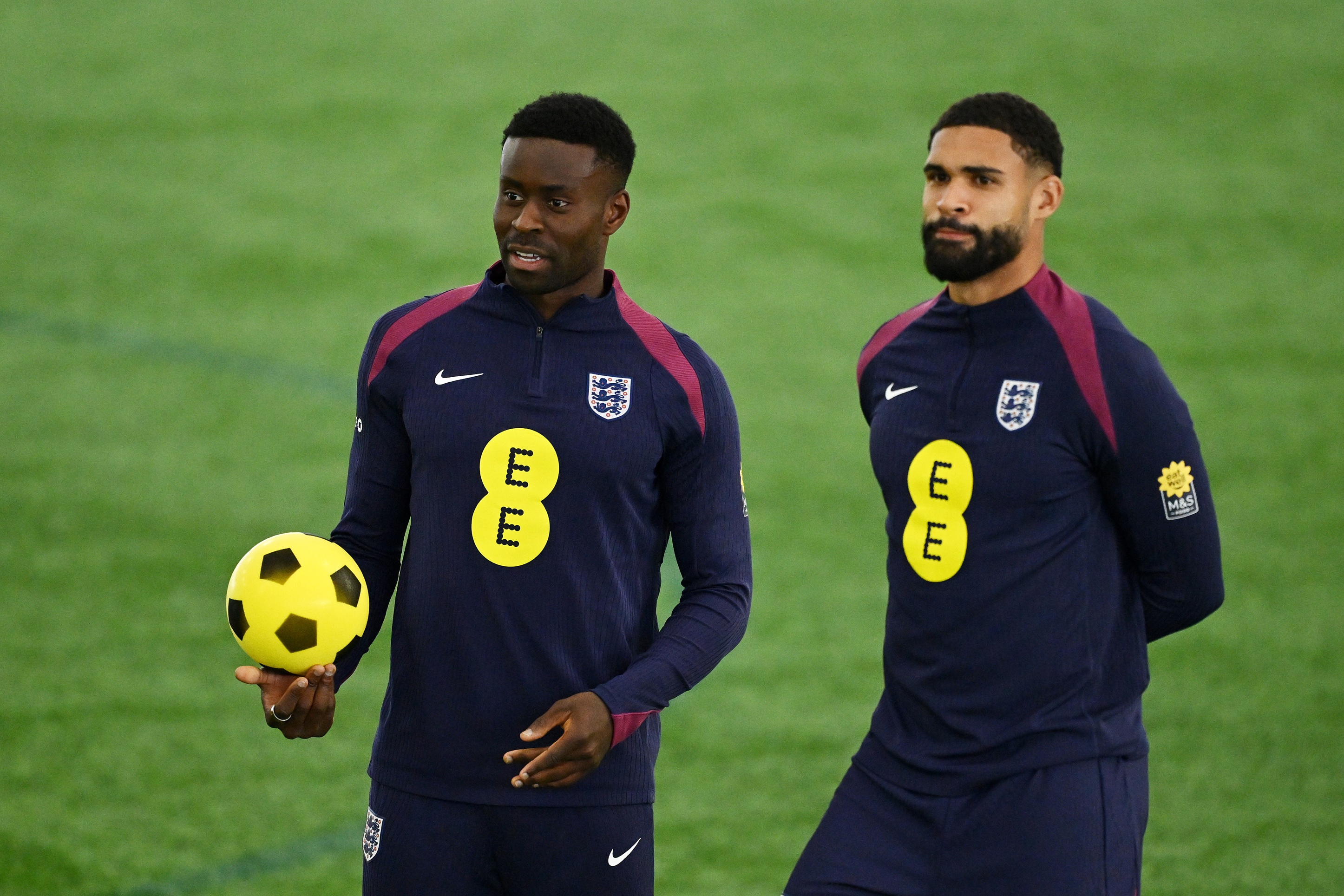 Marc Guehi holds a yellow football while standing next to Ruben Loftus-Cheek.