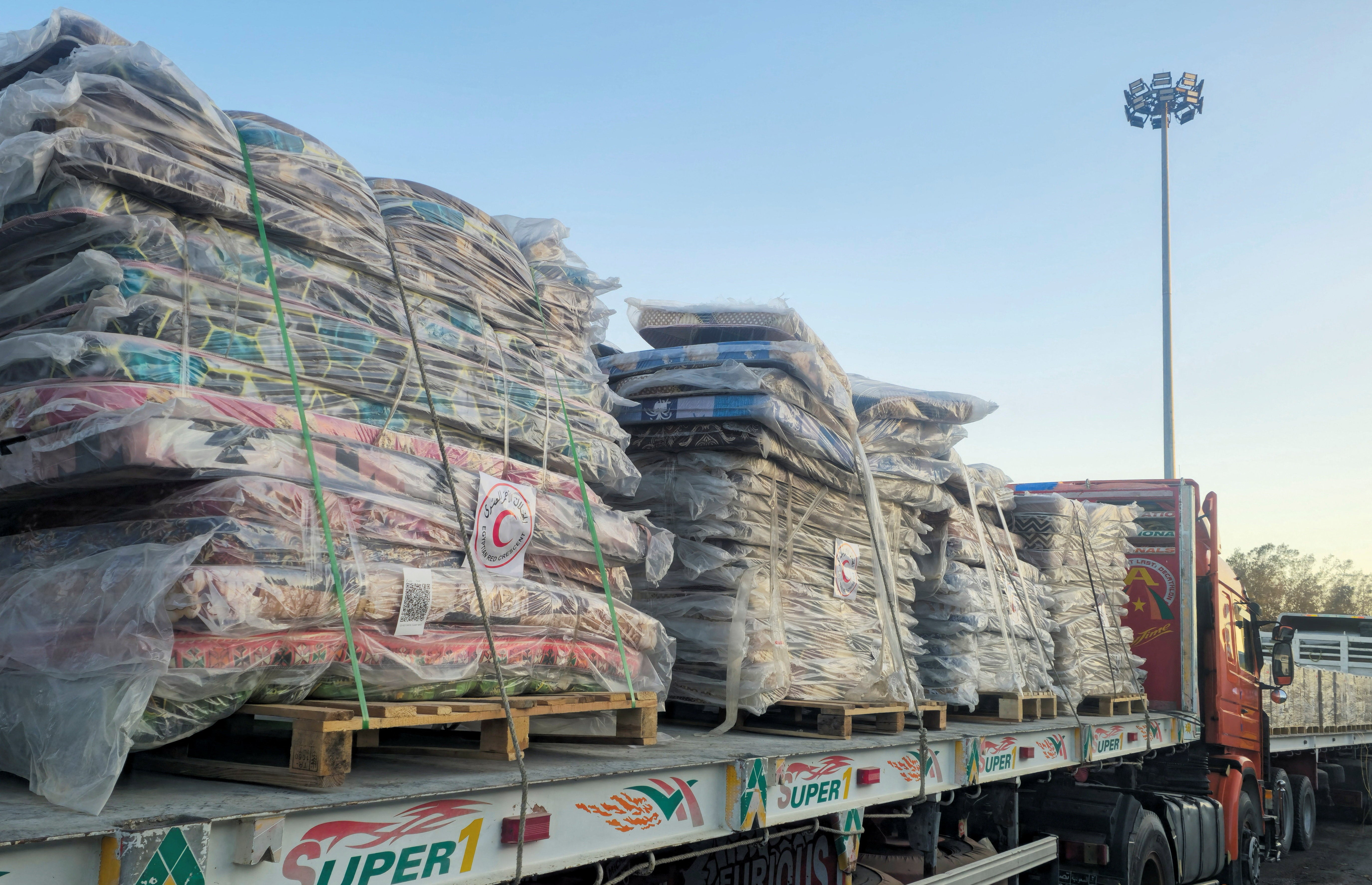 Trucks carrying humanitarian aid line up at the Rafah border on the Egypt side and enter the crossing into the Gaza Strip, after a ceasefire between Israel and Hamas in Gaza went into effect