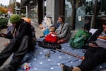 Andy Siebe, center, sits among protester's belongings and donated supplies near the U.S. Immigration and Customs Enforcement building on Wednesday, Oct. 8, 2025 in Portland, Ore. After police cordoned off the site in front of the ICE building Tuesday, protesters and volunteers set up donation and aid posts on adjacent streets.