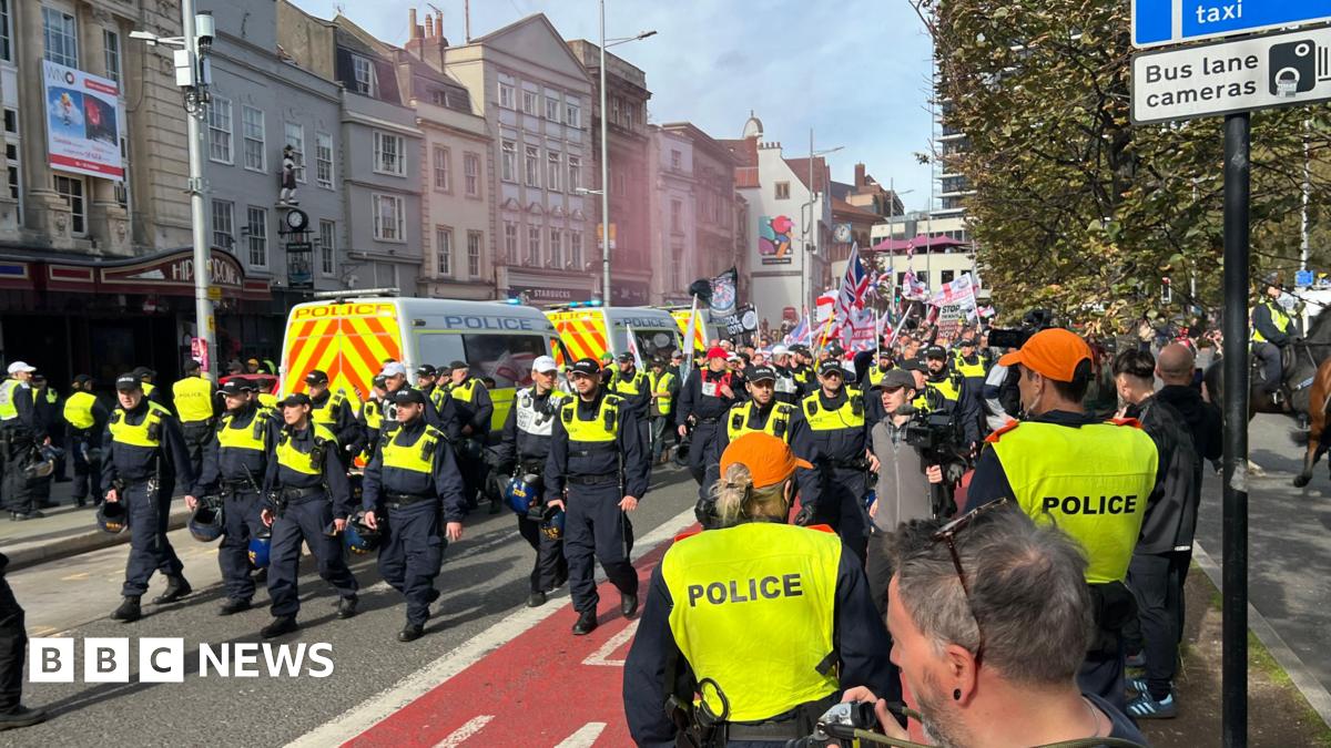 Large police presence in front of marching protesters waving Union flags and English flags