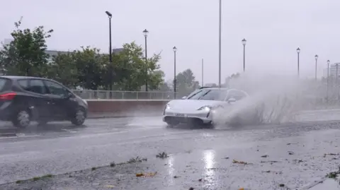 Pacemaker Water splashes around a grey car near Belfast.