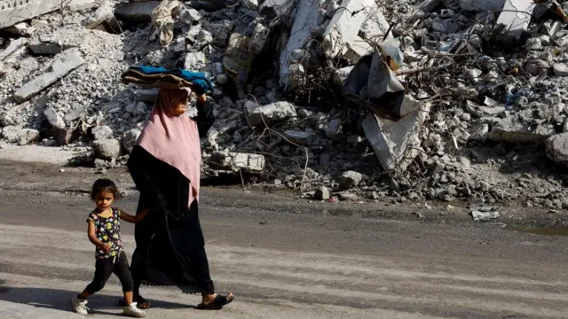 Palestinians walk by strikes