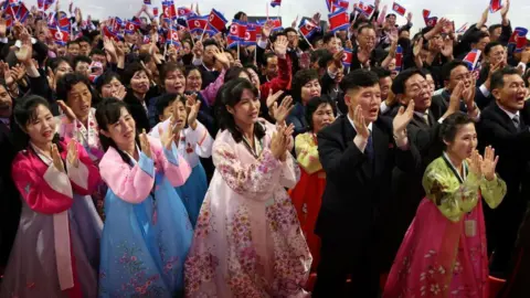 Reuters Performers dressed in colourful traditional costumes clap and raise North Korean flags during the event