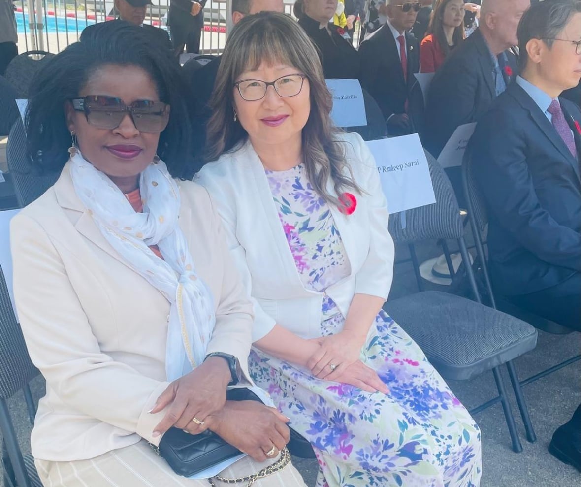 Two women sit together at an outdoor event.