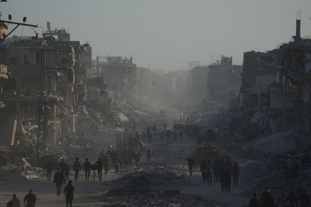 Displaced Palestinians carry their belongings as they walk along the heavily damaged Al-Jalaa Street in Gaza City on Saturday.