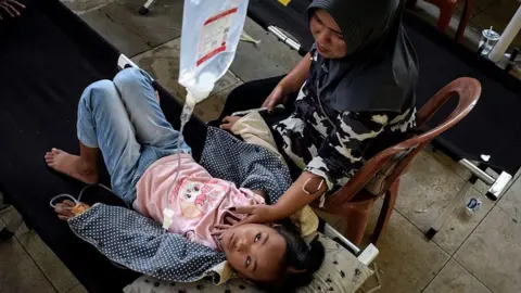 Getty Images Salwa Nur Azmi, an elementary school student gets treatment in a makeshift clinic whilst she is suffering from food poisoning, after eating at the government's free meal programme