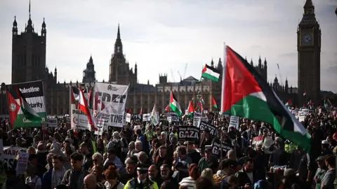 Getty Images A large crowd of protesters holding Palestinian flags and placards are gathered with the Houses of Parliament in the background.