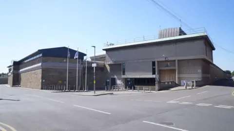 Danny Lawson/PA The outside of Wakefield Prison, an austere brutalist building with flags placed close to the entrance.