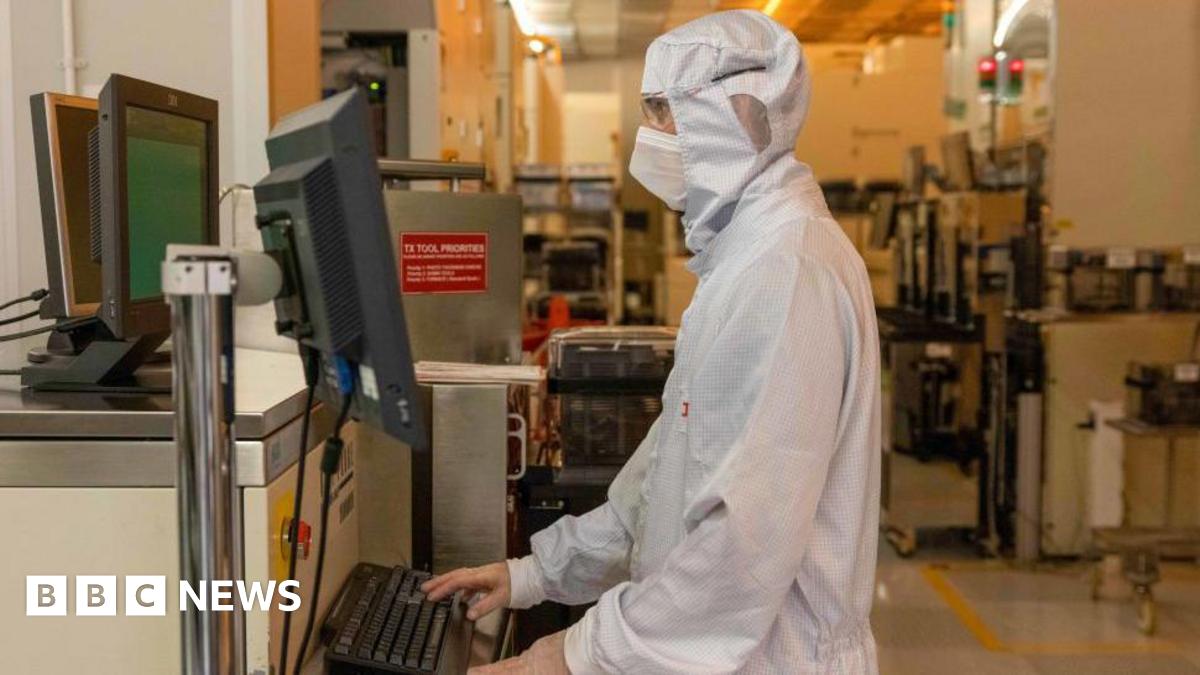 A worker dressed in white specialised personal protective equipment uses a computer in a silicon semiconductor manufacturing plan owned by Nexperia in the UK.