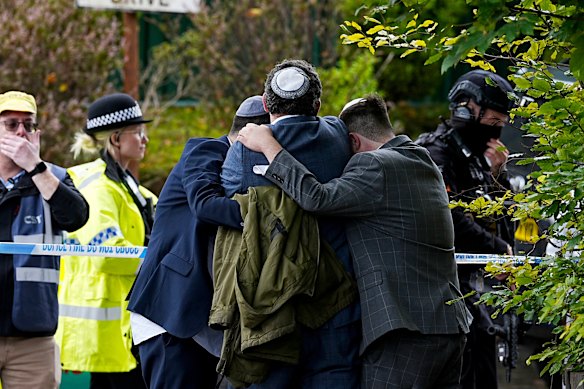 Members of the Jewish community comfort each other near the Heaton Park Hebrew Congregation synagogue.