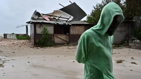 EPA A man walks by a house damaged by the preliminary winds of Hurricane Melissa 