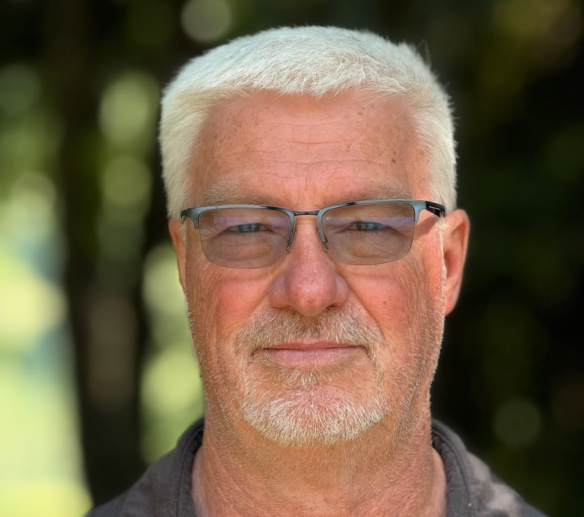 A man with tinted glasses and short white hair. 