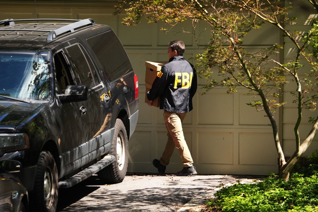 FBI agents carry boxes outside the home of John Bolton, former national security adviser to President Trump, August 22, in Bethesda, Maryland.