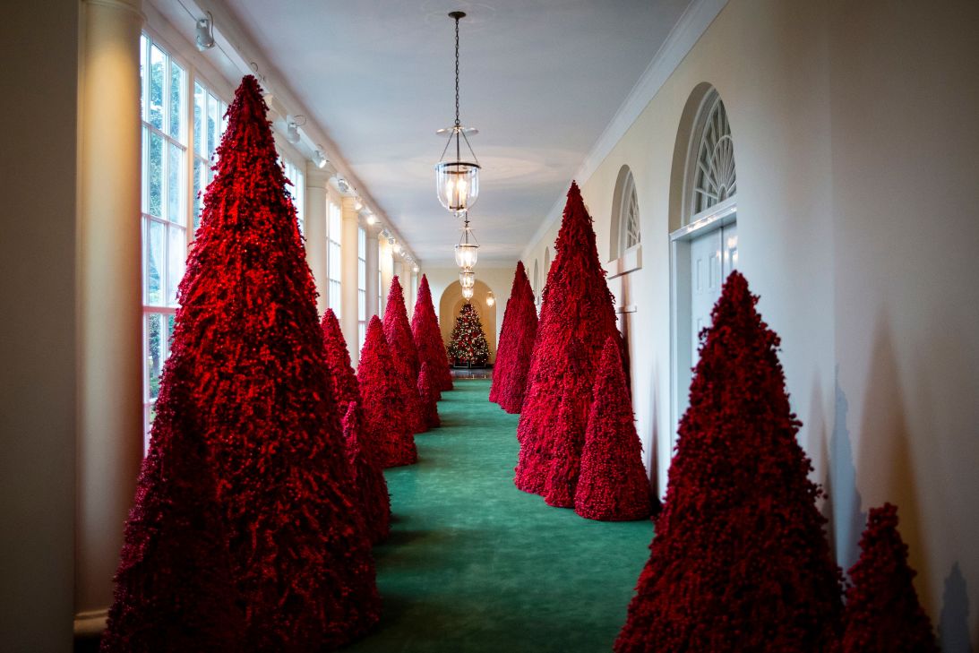 Red Christmas trees line a hallway in the East Wing during a preview of the White House holiday decor on November 26, 2018.