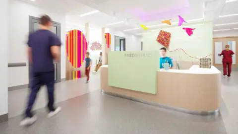 TODD Architects Shows an artist's impression of inside a hospital unit with a reception desk saying PAEDIATRICS