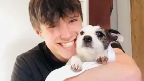 Family handout Young man hugging a small dog