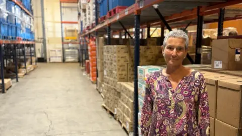 Nelle Miller stands in front of warehouse boxes