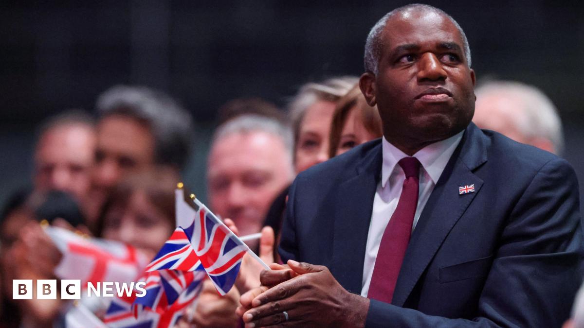 David Lammy holds a small union flag as he watches Keir Starmer's conference speech