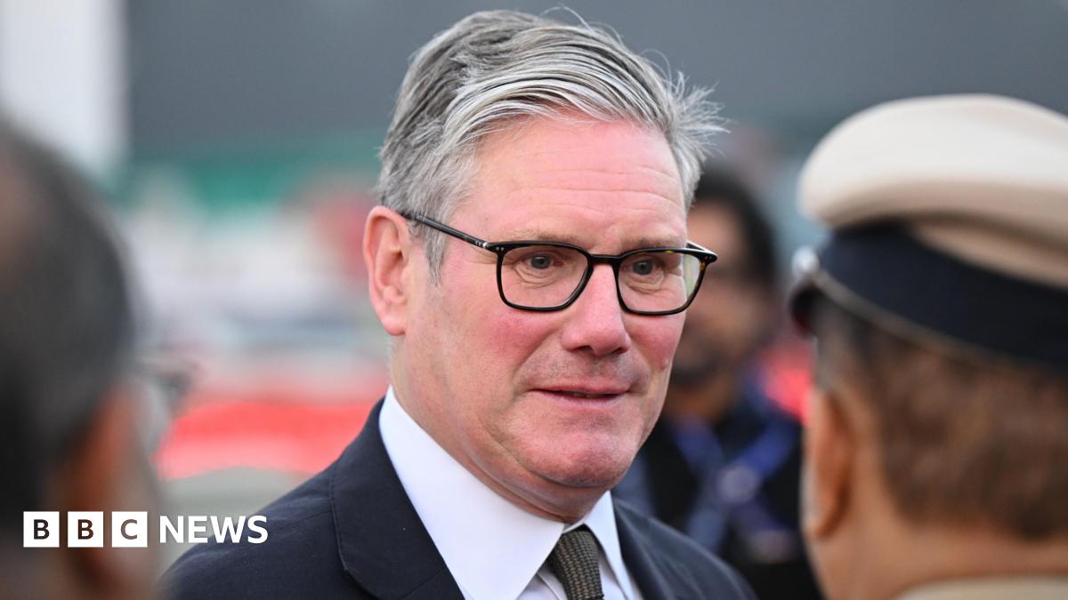 Sir Keir Starmer wearing black rimmed glasses; a white shirt, patterned tie and black jacket.