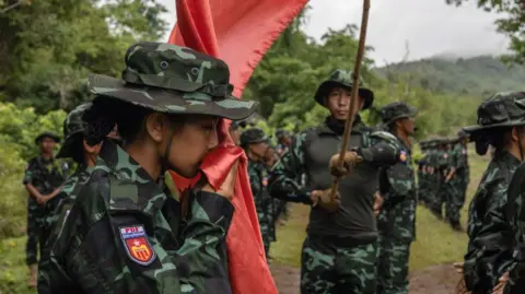 Getty Images A new member of the Special Operation Group- SOG (a branch of the People's Defense Force or PDF) kisses the flag at a military graduation event.