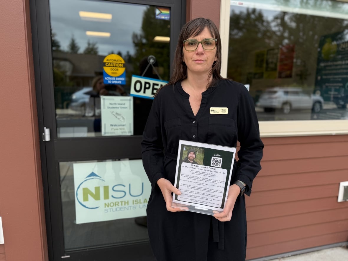 A woman in a black dress holds up a photo of a student who died. 