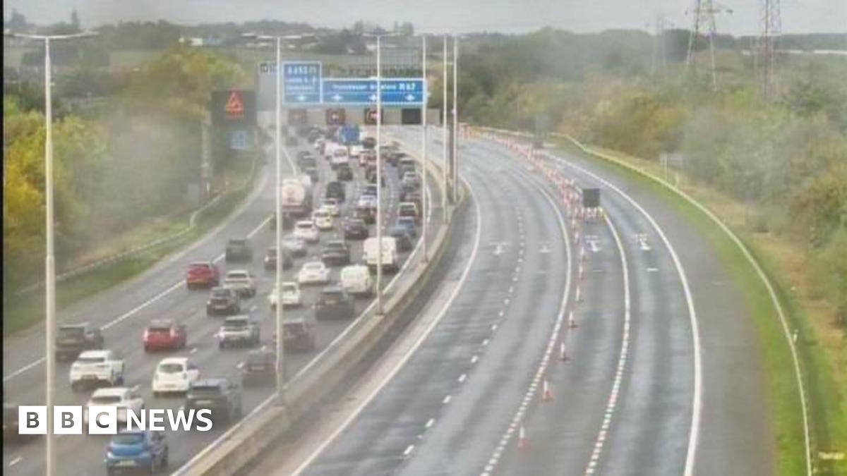 CCTV still image of traffic jams on one side of a motorway and four empty lanes on the other side. It appears to be raining.