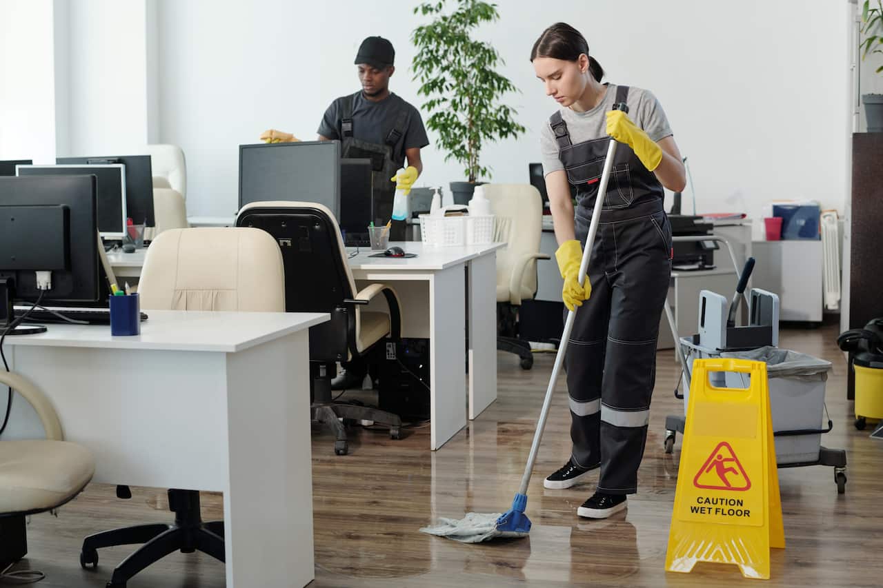 A man and a woman clean an office.